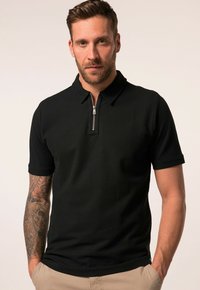 Černé polo tričko s krátkými rukávy, zapínáním na zip u límce a žebrovanou texturou. Disponuje přiléhavým střihem a jemnými švy.