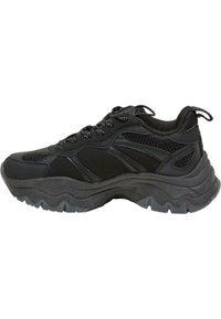 Černá sportovní bota s prodyšným a syntetickým svrškem, texturovanou podrážkou, kulatou špičkou a kontrastním prošitím. Šněrovací design a polstrovaný límec.