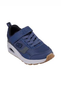 Zapatilla deportiva azul con materiales de malla y sintéticos, suela de goma, cordones frontales y tira de velcro. Presenta un diseño texturizado y un logo.