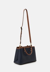 Sac à main synthétique bleu marine avec accents en cuir marron, doubles poignées et une bandoulière amovible. Comprend une quincaillerie dorée et un design structuré.