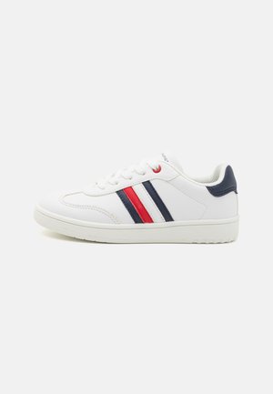 White sneakers with a smooth leather surface, featuring red and navy blue stripes on the side, and a textured rubber sole.