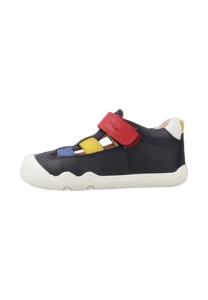 Chaussure enfant bleu marine avec semelle blanche, bride rouge, accents jaunes et bleus, et bout fermé avec découpes respirantes.