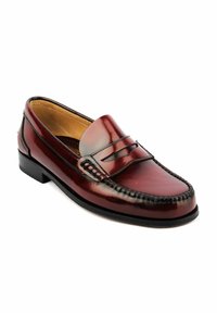 Mocasines de piel marrón oscuro pulido para hombre con costura moc toe y suela negra, mostrados en un ángulo ligero sobre un fondo blanco.
