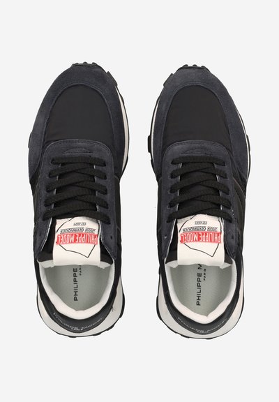 Schwarze Wildleder- und Nylon-Sneaker mit abgerundetem Zeh, strukturierten Akzenten und kontrastierenden weißen Elementen. Sichtbares Markenlabel auf der Zunge.