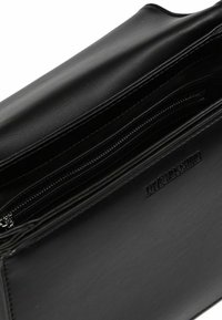 Schwarze Leder-Clutch mit Reißverschlussfächern, strukturiertem Oberflächenmaterial und geprägtem Markenlogo. Verfügt über mehrere Kartenfächer und ein glattes Innenfutter.