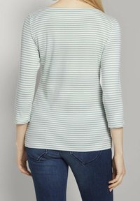 Hellblaue und weiße gestreifte Langarmbluse mit einem Boot-Ausschnitt und 3/4-Ärmeln, kombiniert mit dunkelblauen Jeans.