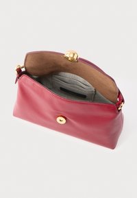 Czerwona skórzana kopertówka o gładkiej fakturze, zamknięcie z złotymi okuciami oraz wnętrze wyściełane beżowym zamszem z małą kieszonką.