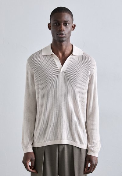 Light beige long-sleeve polo with a textured knit pattern and a contrasting white collar. Features a V-neck and ribbed cuffs.