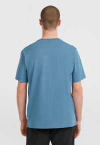 T-shirt en coton bleu à manches courtes avec un col rond. Texture lisse et coupe décontractée. La vue arrière montre un design simple et sans embellissement.