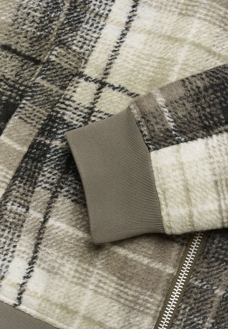 Kariertes Fleece-Jackett in Braun- und Cremetönen, mit strukturiertem Finish und gestricktem Bündchen. Silberner Reißverschluss entlang der Vorderseite.