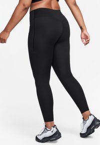 Sorte tights med høy midje, glatt tekstur og strømlinjeformet passform. Kombinert med hvite og svarte joggesko med luftdemping.