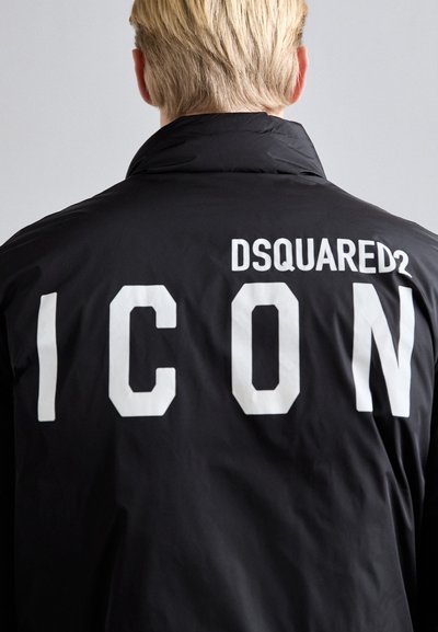 Black jacket featuring white text on the back reading "DSQUARED2 ICON." The material appears smooth with a casual design and standard collar.