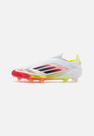 Fußballschuhe mit einem überwiegend weißen Obermaterial, roten und gelben Akzenten, strukturierten Oberflächen und einem aerodynamischen Design. Klare Stollen an der Sohle.