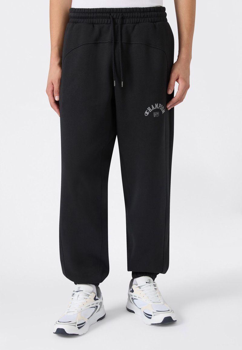 Schwarze Sweatpants mit einem elastischen Bund, gesticktem "Champion"-Logo auf der Vorderseite und schmal zulaufenden Bündchen. Weicher Stoff mit Seitennähten.