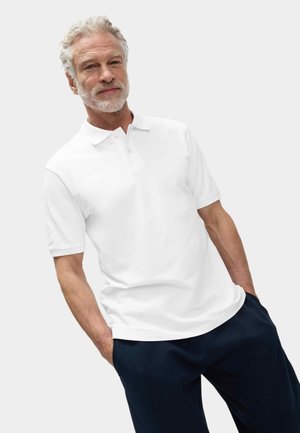 Witte poloshirt met een klassieke kraag en korte mouwen. Draagt men met marineblauwe broek, die een ontspannen pasvorm en zijzakken heeft.