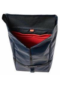 Sac imperméable bleu marine avec un design à rabat, doublure intérieure rouge et un compartiment zippé. Présente une sangle d'accent noire.