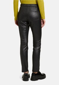 Zwarte neplederen broek met een slim fit, elastische tailleband en twee achterzakken, met een gladde textuur en glanzende afwerking.
