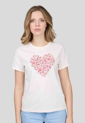 T-shirt en coton crème avec un motif de cœur composé de motifs floraux roses. Manches courtes et col rond avec une légère bordure.