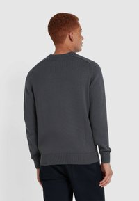 Grauer gestrickter Pullover mit gerippten Bündchen und Saum, der einen Rundhalsausschnitt und eine strukturierte Oberfläche aufweist. Von hinten betrachtet.