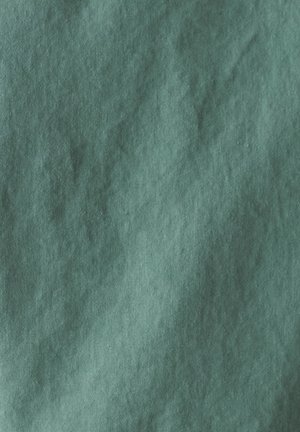 Tirkizna tkanina s lagano teksturiranom površinom, koja prikazuje gradijentni efekt svjetlijih i tamnijih nijansi. Glatka tekstura s suptilnim varijacijama.