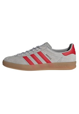 Baskets Adidas Gazelle gris clair avec des bandes rouges, languette de talon rouge, semelle en gomme et lacets gris, vues de côté extérieur.