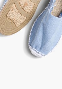 Espadrille en toile bleu clair avec un bord cousu blanc, dotée d'une semelle en jute tressé et d'un dessus en tissu texturé.