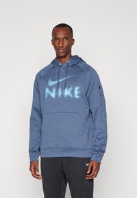 Modrá mikina s kapucňou vyrobená z textúrovanej látky, na ktorej sa nachádza výrazné svetlomodré logo Nike. Obsahuje klokanie vrecko a detail bočného zipsu.