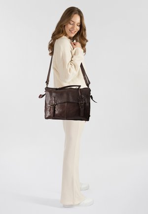 Borsa a tracolla in pelle marrone con due tasche frontali, cinturino regolabile e hardware decorativo. Texture liscia, forma rettangolare e design minimalista.