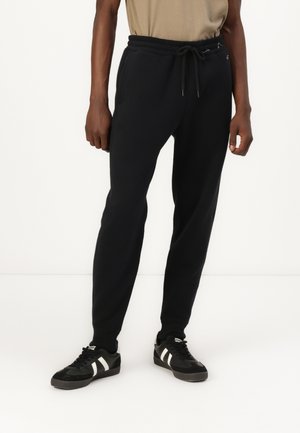 Schwarze Jogginghose mit tailliertem Design, elastischem Bund und Kordelzug. Verfügt über zwei Seitentaschen und minimales Hardware-Detail.