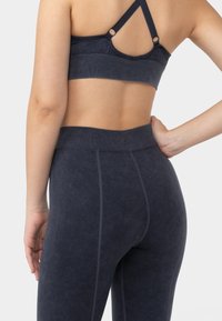 Soutien-gorge de sport marine et leggings taille haute en tissu doux et texturé. Le soutien-gorge présente des bretelles croisées ; les leggings possèdent des détails de couture contrastants.