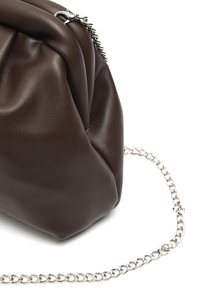 Mørkebrunt blødt læder håndtaske i pose-stil med sølv metal kædestrop på hvid baggrund.