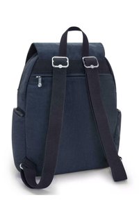 Námořnický látkový batoh s přehnutým víkem, zesíleným šitím, nastavitelnými černými popruhy a stříbrnými kovovými detaily. Viditelné jsou dvě boční kapsy.