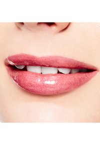 Colore lucido per labbra in una delicata tonalità di rosa con una finitura liscia e strutturata, che mette in evidenza labbra piene e denti bianchi perlacei.