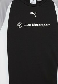 Tricou sportiv negru cu accente gri, dintr-un material texturat. Afișează logo-urile BMW și Puma, cu cuvântul "Motorsport" în litere albe.