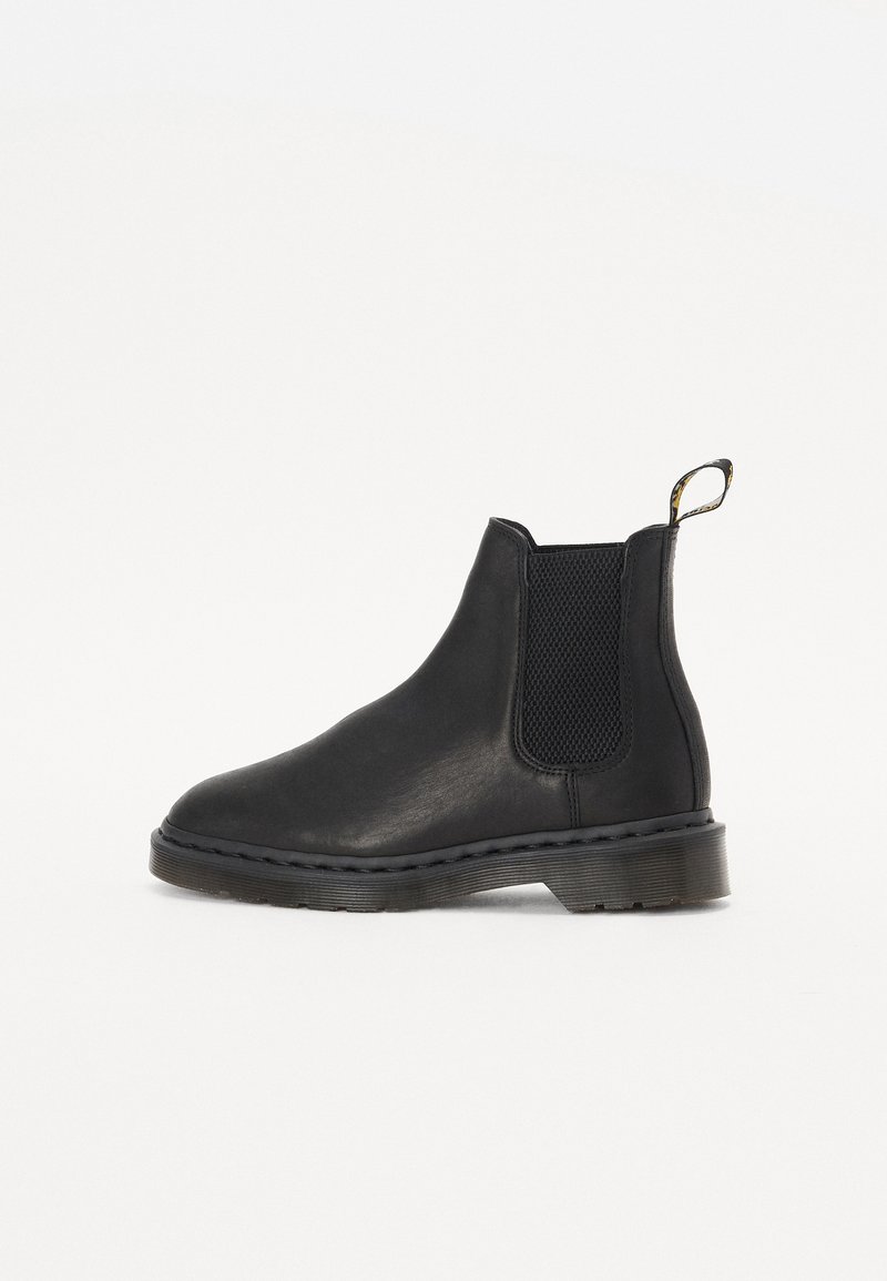 Botte Chelsea en cuir noir avec panneau latéral élastique, languette au talon et semelle en caoutchouc épaisse, vue de côté sur fond blanc.