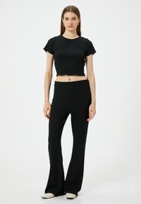 Zwart tweedelig outfit met een gestructureerd, cropped top met korte mouwen en een hoge taille, flared broek. Gladde stoffen afwerking met subtiele details.