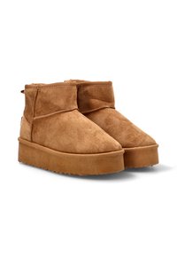 Botas de tobillo de ante marrón con una suela de goma texturizada y plana, y detalles de costura simples, que presentan un perfil bajo y un diseño de punta redondeada.