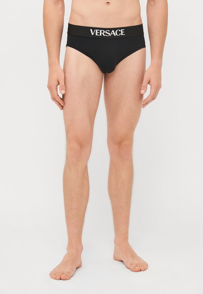 Zwarte boxershorts voor mannen met een brede elastische tailleband waarop het "VERSACE"-logo in het wit staat. Glad materiaal, aansluitend ontwerp, minimale bedekking.
