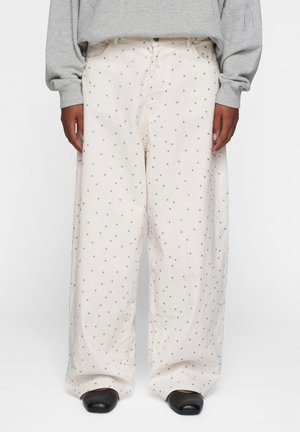 Pantaloni a gamba larga in tessuto crema con pois grigi. Presentano una chiusura frontale con bottone, una vestibilità dritta e tasche visibili.