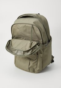 Olive green backpack with a main zippered compartment, front pocket flap with snap closure, and adjustable shoulder straps for comfort.