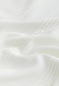 Tessuto bianco morbido con sottili linee diagonali in rilievo che creano un motivo testurizzato sulla superficie.