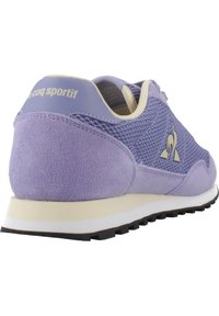 Chaussure de sport violette en mesh et suède, avec une semelle intermédiaire blanche, une semelle extérieure en caoutchouc texturé et un logo discret sur le talon.