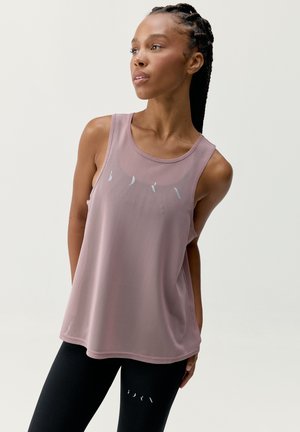 Tirante rosa ligero y sin mangas con un ajuste holgado, que presenta letras plateadas. Combinado con leggings negros con detalles recortados.