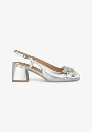Scarpa slingback metallica argento con tacco a blocco, punta arrotondata e fiocco decorativo con strass sulla parte anteriore. Texture liscia, design minimale.
