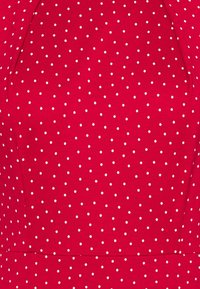 Abito in tessuto rosso con pois bianchi, design strutturato, texture liscia e silhouette aderente.