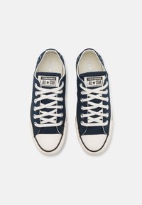 Baskets en toile navy avec semelles en caoutchouc blanc, bout rond et lacets blancs contrastants. Présente le logo All Star sur la languette.