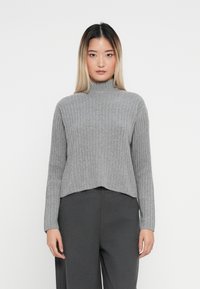 Grå ribbestrikket turtleneck genser med cropped design, lange ermer og en subtil tekstur, kombinert med mørkegrå høytlivsbukser.