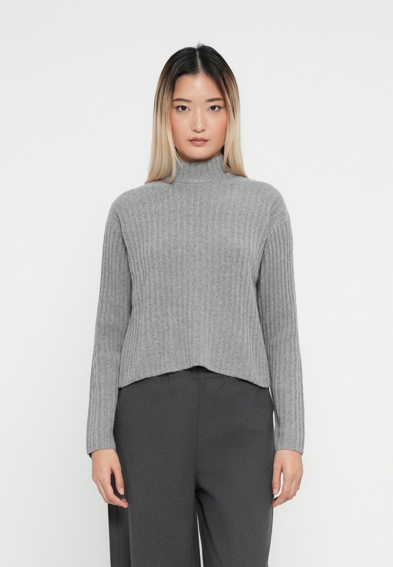 Grå ribbestrikket turtleneck genser med cropped design, lange ermer og en subtil tekstur, kombinert med mørkegrå høytlivsbukser.