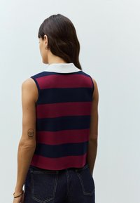 Débardeur en polo à rayures horizontales bleu marine et bourgogne, avec un col blanc. Le tissu semble lisse avec un design ajusté.