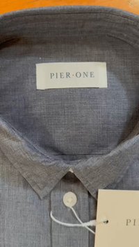 Siv srajcni zgornji del z blago teksturo, s koničastim ovratnikom in blagovno oznako "PIER ONE." Ima eno gumbasto zapiranje.